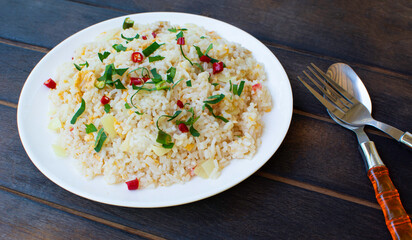 Fried rice on a dark wooden floor. Thai food. One dish appetizing cutlery.