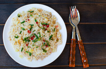 Fried rice on a dark wooden floor. Thai food. One dish appetizing cutlery.