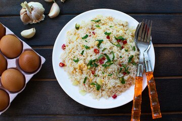 Fried rice on a dark wooden floor. Thai food. One dish Cutlery, side dishes, spices, chicken eggs.