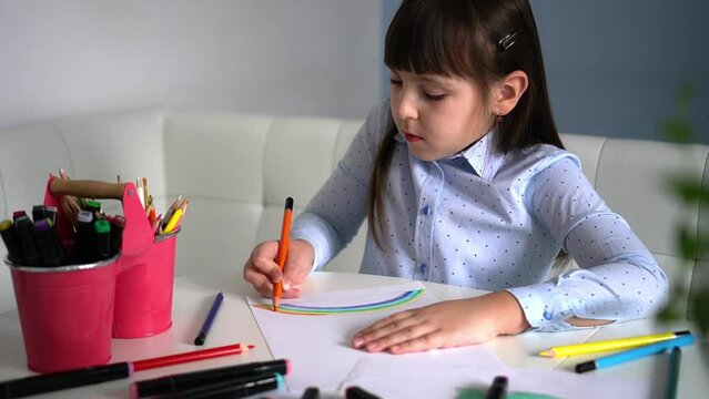 Kids creativity. Child little girl drawing rainbow with colored pencils on paper at home