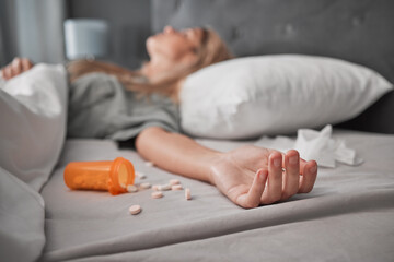 Depression, mental health and overdose with pills and woman in bedroom for anxiety, suicide and death. Sad, medicine and grief with girl lying in bed after taking drugs for pain, trauma and problem - obrazy, fototapety, plakaty