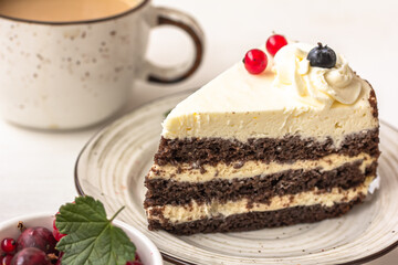 Delicious berry cake. A layered cake with white cream on the plate, a white ceramic cup, a bowl of red berries on white table