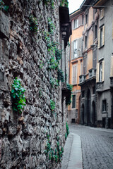 Close up of ancient wall on a street with buildings in Bergamo, Italy