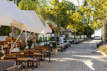 Street view of an outdoor terrace with tables and chairs in restaurant. A street restaurant on the embankment of the ancient city of Side, Turkey.