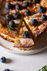 lush sponge cake with blueberries, powdered sugar and rosemary