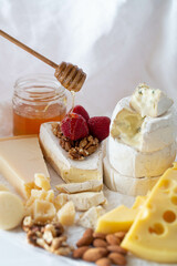 cheeses with nuts honey and raspberries on a white background