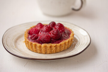A tartlet shell with red berries, A piece of strawberry cake on white background.