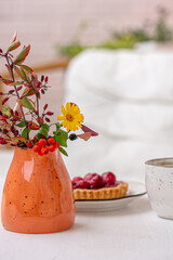 Autumn still life mock up.  Autumn bouquet in an orange colored vase, a dessert on white background,.  Autumn decoration, copy space.