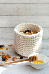 Knitted basket made of natural cotton with a nut mixture. Healthy eating. Nuts, raisins and honey. Eco-friendly interior design. Eco packaging. Ingredient for preparing healthy food.