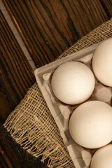 White chicken eggs in a cardboard box on the table. Close-up, selective focus.