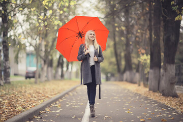 girl with umbrella posing in autumn park, october landscape lonely woman holding a red umbrella