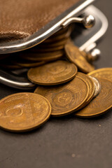 Old coins of the USSR and a vintage wallet made of brown leather on a wooden surface.