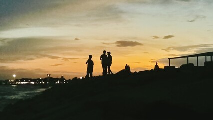 Obraz premium silhouettes of people on the beach at sunset
