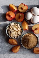 Plum pie in process. Fresh ingredients on a table. Top view photo of plums, almonds, demerara sugar, eggs. Sweet cake ingredients closes up. 