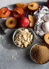 Sweet cake ingredients on a table. Close up photo of plums, eggs, brown sugar and almonds. Baking  fruit pie. Healthy eating concept. 