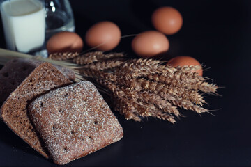 Fresh loaves of bread with wheat and gluten on a black table. Bakery and grocery concept. Fresh,...