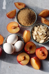 Sweet cake ingredients on a table. Close up photo of plums, eggs, brown sugar and almonds. Baking  fruit pie. Healthy eating concept. 