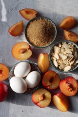 Plum pie in process. Fresh ingredients on a table. Top view photo of plums, almonds, demerara sugar, eggs. Sweet cake ingredients closes up. 