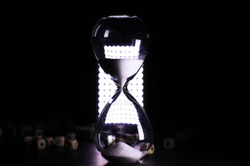 Sand running through the bulbs of an hourglass measuring the passing time in a countdown to a...