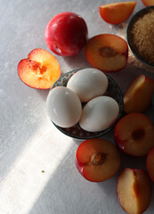 Sweet cake ingredients on a table. Close up photo of plums, eggs, brown sugar and almonds. Baking  fruit pie. Healthy eating concept. 