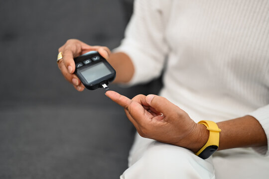 Mature diabetic woman using glucose meter on finger, measuring blood glucose. Diabetes and health care concept