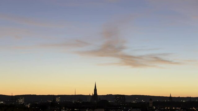 Time lapse shot of the cities of Neu-Ulm and Ulm with Ulm Minster while colorful dusk in blue and yellow seen from hill in city part &bdquo;Pfuhl&ldquo; of Neu-Ulm (Kapellenberg)