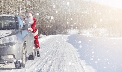 Fototapeta na wymiar Santa Claus comes with gifts from the outdoor. Santa in a red suit with a beard and wearing glasses is walking along the road to Christmas. Father Christmas brings gifts to children.