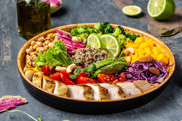 Buddha bowl with kale salad, chicken fillet, quinoa, avocado, pumpkin, tomato, broccoli, red cabbage, chickpea, watermelon radish, fresh lettuce salad, nuts
