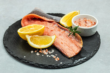 salmon fillet with rosemary and salt on light board. Pescetarian seafood for cooking. fish fillet with cooking ingredients, herbs and lemon. top view