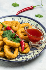 Rings of squid with lemon and sauce on a light background. Snack to beer. banner, menu, recipe place for text, top view