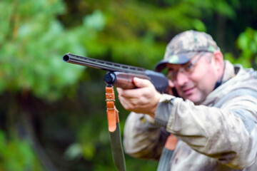 Shotgun barrel, hunting gun in selective focus in the hands of a blurred hunter.