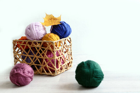 Autumn is the time for knitting warm cozy things: a maple leaf on multi-colored skeins in a decorative box, a gray background, a place for text