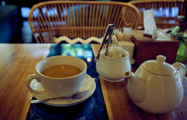 White ceramic tea set. Cup with green tea, teapot and sugar bowl on restaurant table