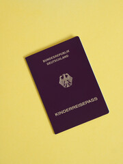 Burgundy red biometric german youth passport covers called Reisepass (Bundesadler), ID or proof of European Union citizenship for international travel on yellow background. copy space