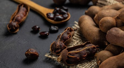 Tropical fruits, Tamarindo beans in shell on a brown butchers block on a dark background, healthy fruit. banner, menu, recipe place for text, top view