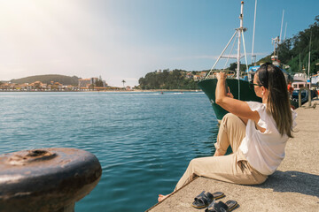 mujer sentada haciendo fotos en un puerto pesquero