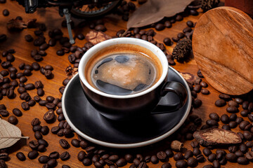 Czarna kawa americano long black w filiżance do kawy na drewnianym stole pełnym świeżo palonych ziaren kawy - obrazy, fototapety, plakaty