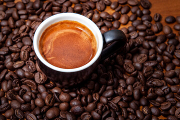 Kawa espresso w czarnej filiżance na stole pełnym świeżo palonych ziaren kawy - obrazy, fototapety, plakaty