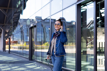 Fototapeta premium Journey. Young woman coming out of the airport talking on the phone.