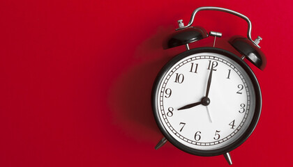 vintage old black alarm clock on red background	