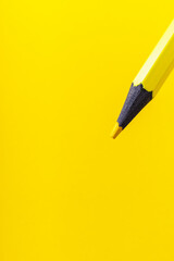 Colored pencil close-up with selective focus on the stylus and a blurred yellow background. Copy space