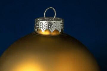 Closeup of a golden christmas bauble on blue background. Selective focus