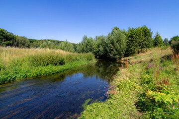 Summer landscape view with Geleenbeek river with trees and grass along the water, Spaubeek is a village in the Dutch province of Limburg, It is located in the municipality of Beek, Netherlands.