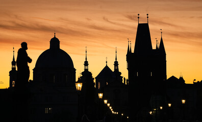 Vintage street light in foreground of an amazing silhouette landscape with Prague architecture next to Charles Bridge and Old Town clock in background. Travel to Czech Republic.
