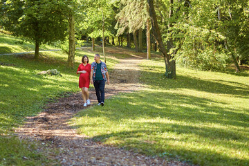 Fototapeta premium Lovely pregnant couple walking in a park