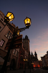 Fototapeta na wymiar Wide angle view with Old Town Clock Tower in Prague during a beautiful autumn sunrise with vintage street light bulb in foreground. Landmarks of Czech Republic.