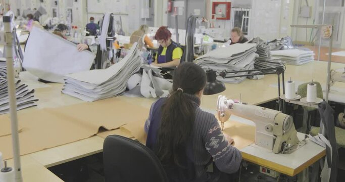 A woman works in a garment factory. A woman works on a sewing machine. Making textiles in a factory