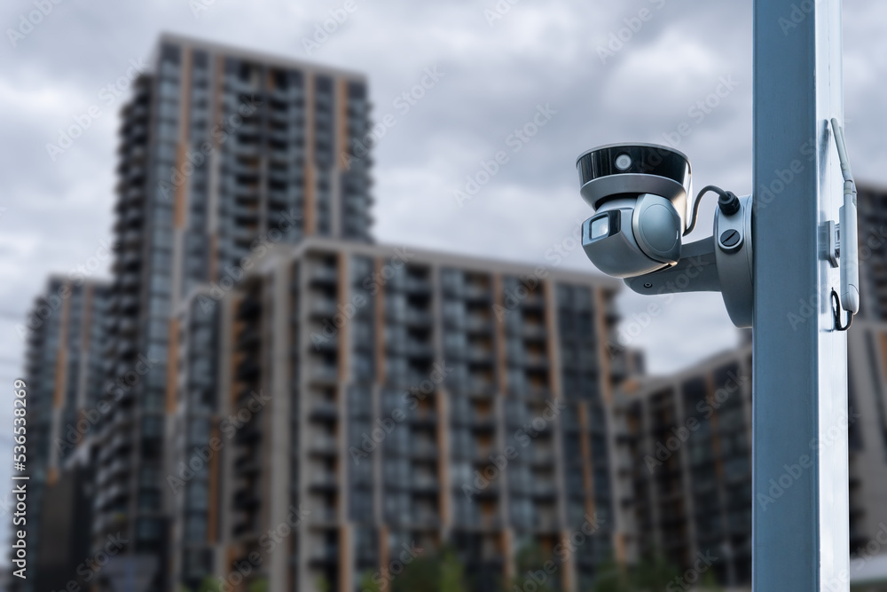 Poster panoramic view of cctv surveillance camera with blurred apartment building background with copy spac