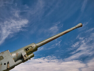 The barrel of a 1942 40mm Bofors gun pointing upward to a blue sky with light white clouds. This was a Swedish made anti-aircraft gun used widely in the Second World War.
