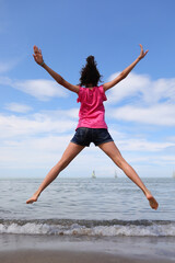 happy girl jumping and rejoicing for joy by the sea